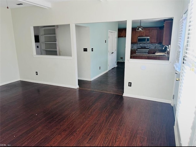 empty room featuring dark wood-type flooring, sink, and beamed ceiling