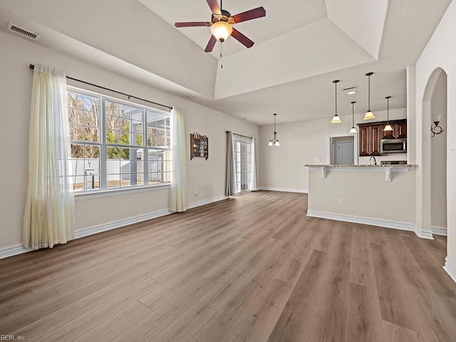 unfurnished living room featuring a healthy amount of sunlight, hardwood / wood-style floors, ceiling fan, and a tray ceiling