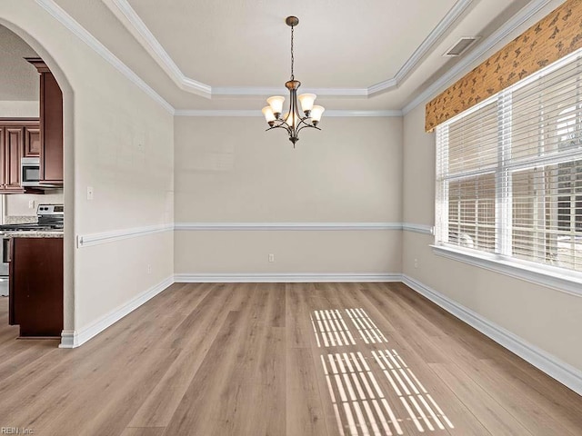 unfurnished dining area with a notable chandelier, ornamental molding, a raised ceiling, and light wood-type flooring