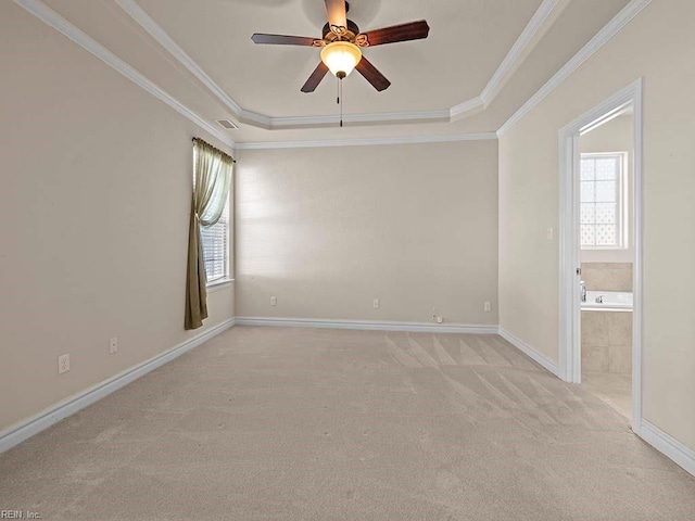 spare room featuring a raised ceiling, ornamental molding, light carpet, and ceiling fan