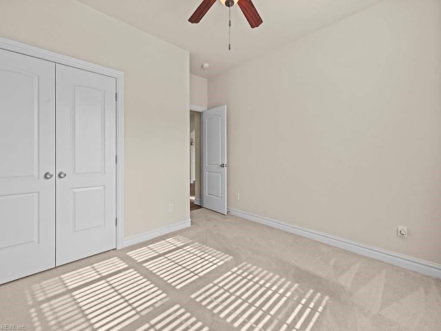 unfurnished bedroom featuring ceiling fan, light carpet, and a closet