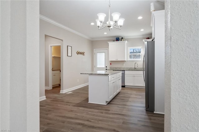 kitchen featuring light stone countertops, stainless steel appliances, white cabinets, and a kitchen island