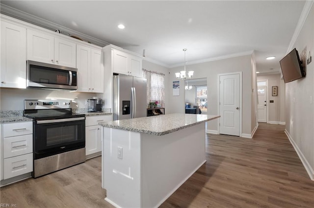 kitchen with white cabinetry, stainless steel appliances, ornamental molding, a kitchen island, and decorative light fixtures