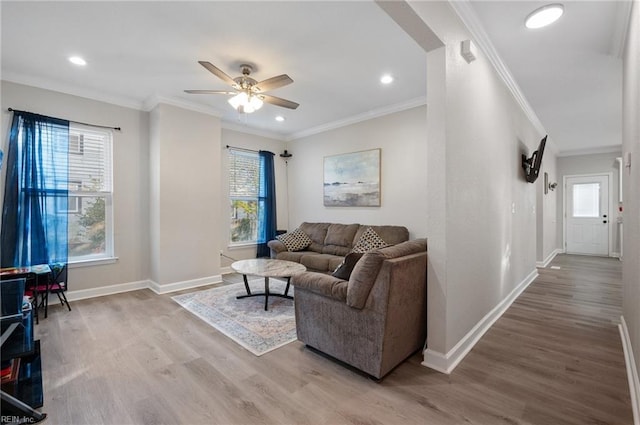 living room with wood-type flooring, ornamental molding, and ceiling fan