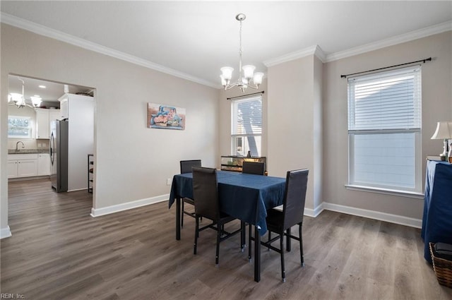 dining area with an inviting chandelier, sink, ornamental molding, and dark hardwood / wood-style floors