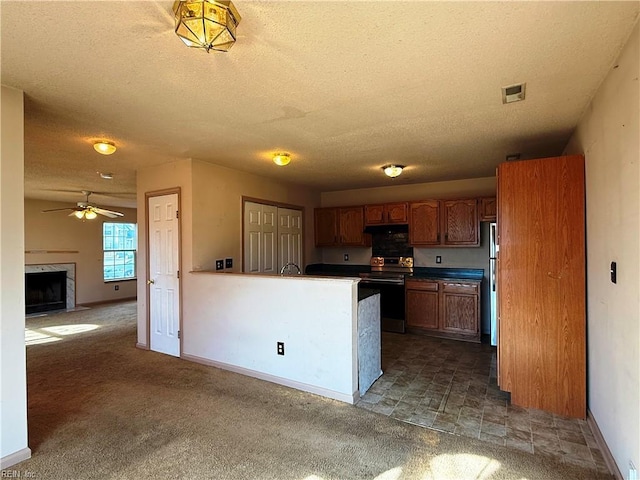 kitchen featuring a premium fireplace, appliances with stainless steel finishes, a textured ceiling, and kitchen peninsula