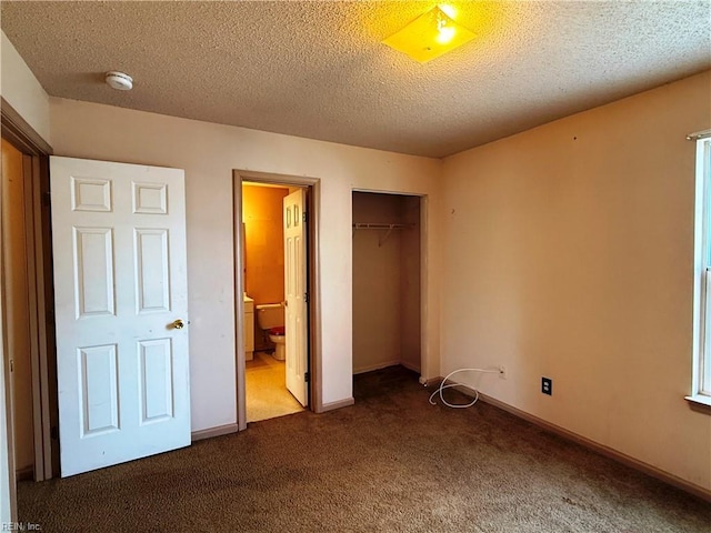 unfurnished bedroom with ensuite bath, a closet, a textured ceiling, and dark colored carpet