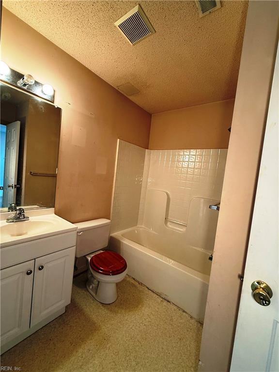 full bathroom with vanity, shower / washtub combination, a textured ceiling, and toilet