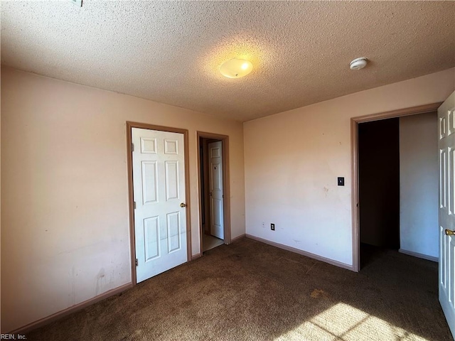 unfurnished bedroom featuring dark carpet and a textured ceiling