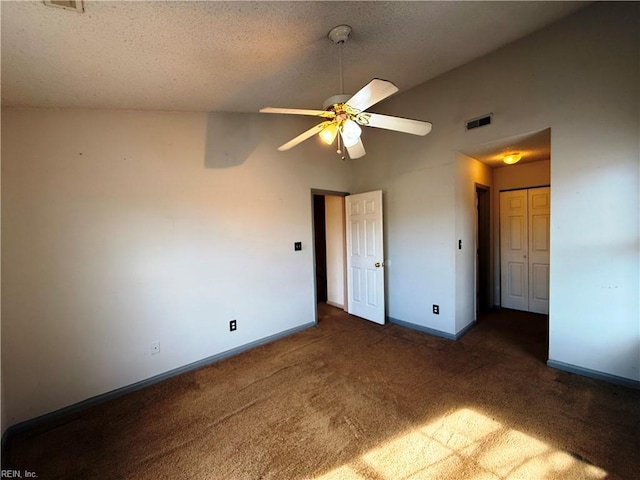 unfurnished bedroom with vaulted ceiling, ceiling fan, dark carpet, and a textured ceiling