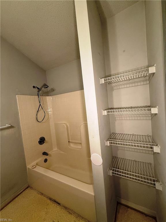 bathroom with washtub / shower combination and a textured ceiling