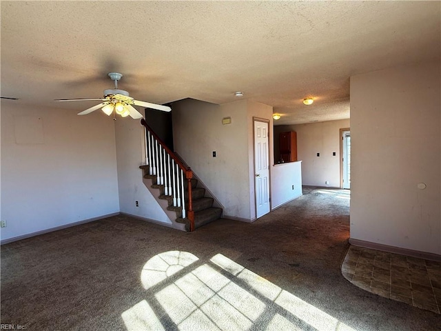 spare room with ceiling fan, a textured ceiling, and dark colored carpet