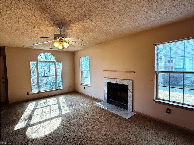 unfurnished living room with ceiling fan, a fireplace, carpet, and a textured ceiling