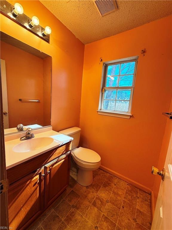 bathroom featuring vanity, toilet, and a textured ceiling