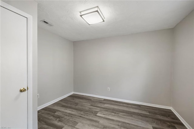 empty room featuring dark hardwood / wood-style flooring and a textured ceiling