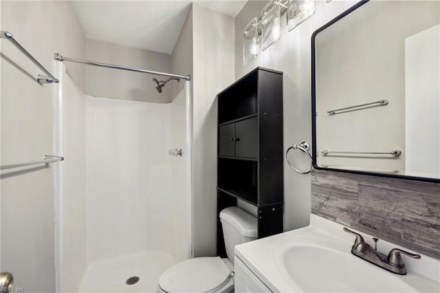 bathroom featuring vanity, backsplash, toilet, and walk in shower