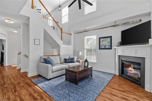 living room featuring hardwood / wood-style flooring, ceiling fan, plenty of natural light, and a high ceiling