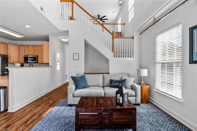 living room featuring dark wood-type flooring, a high ceiling, and a wealth of natural light