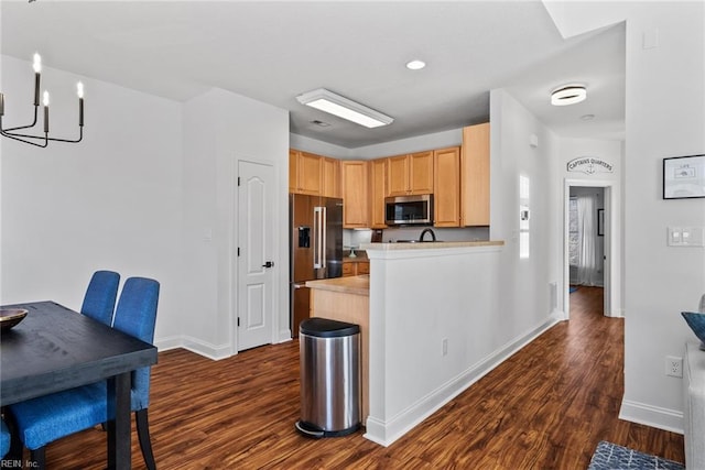 kitchen featuring appliances with stainless steel finishes, light brown cabinets, dark hardwood / wood-style flooring, and kitchen peninsula