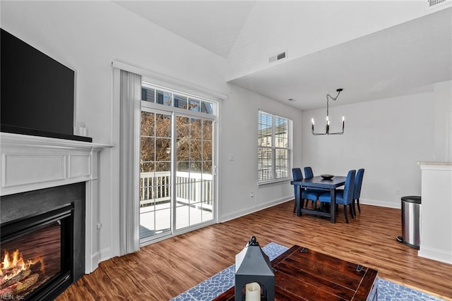 living room featuring wood-type flooring, vaulted ceiling, and an inviting chandelier