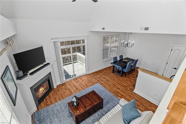 living room with wood-type flooring, lofted ceiling, and ceiling fan with notable chandelier