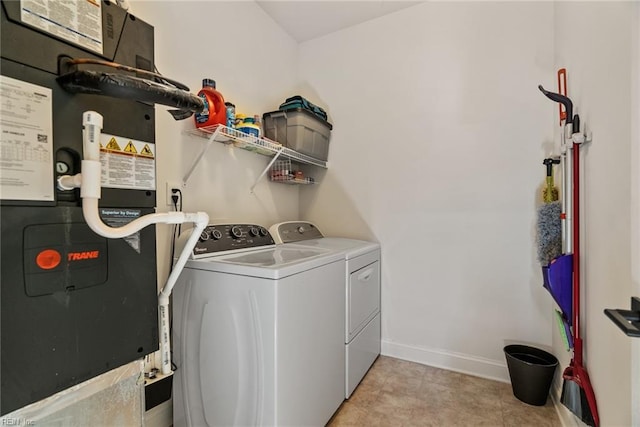 clothes washing area featuring washing machine and dryer, heating unit, and light tile patterned floors