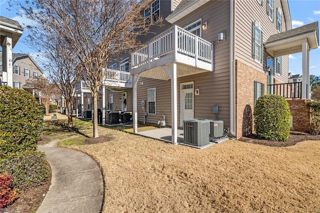 back of house featuring a patio, a balcony, a yard, and central AC