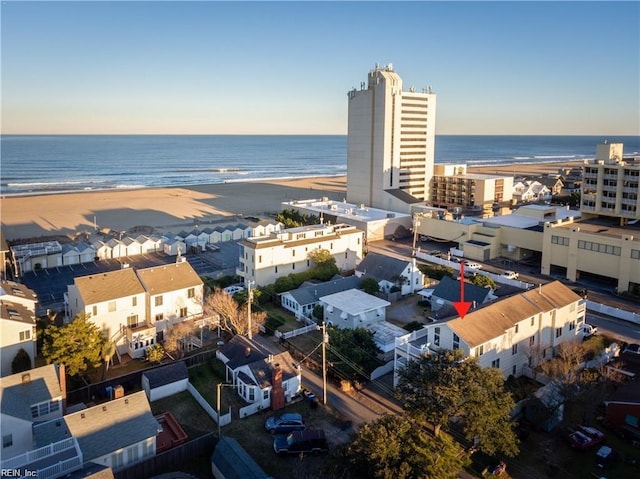 aerial view at dusk featuring a water view and a beach view