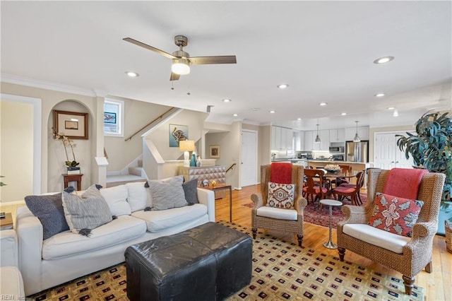 living room with ornamental molding, ceiling fan, and light hardwood / wood-style floors