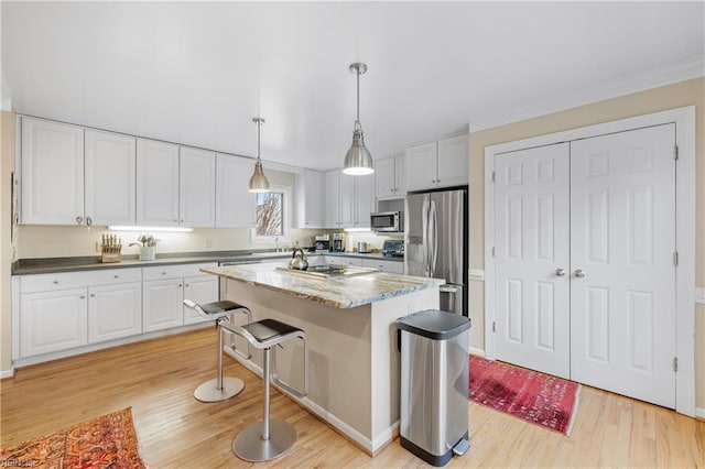 kitchen featuring a kitchen island, appliances with stainless steel finishes, decorative light fixtures, white cabinetry, and light hardwood / wood-style floors