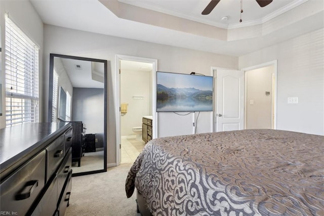 bedroom with ornamental molding, light colored carpet, ceiling fan, a raised ceiling, and ensuite bath