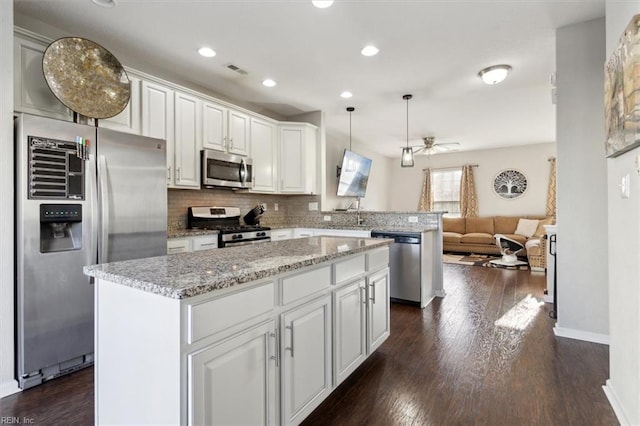 kitchen featuring appliances with stainless steel finishes, hanging light fixtures, a kitchen island, and white cabinets