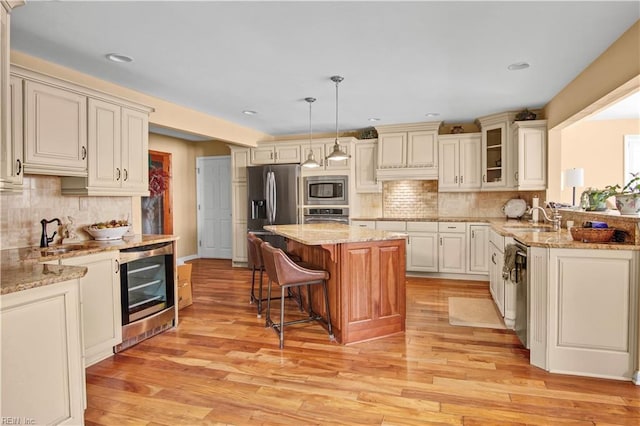 kitchen featuring pendant lighting, a breakfast bar area, stainless steel appliances, wine cooler, and a kitchen island