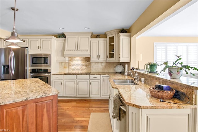 kitchen featuring sink, tasteful backsplash, custom range hood, pendant lighting, and stainless steel appliances