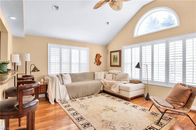 living room featuring high vaulted ceiling, ceiling fan, and light wood-type flooring