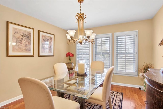 dining area with light wood-type flooring and a notable chandelier