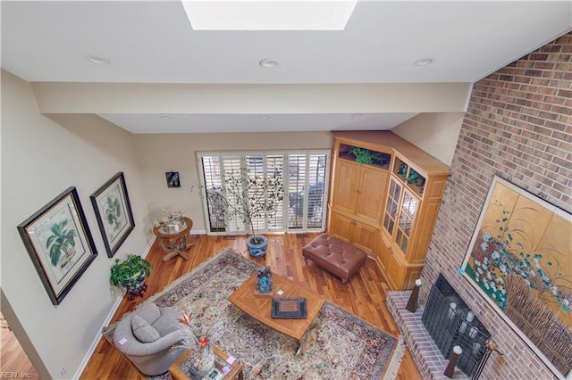 living room featuring a fireplace, a skylight, and light wood-type flooring