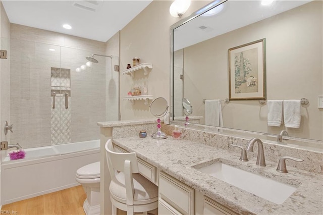 full bathroom featuring tiled shower / bath combo, vanity, hardwood / wood-style floors, and toilet