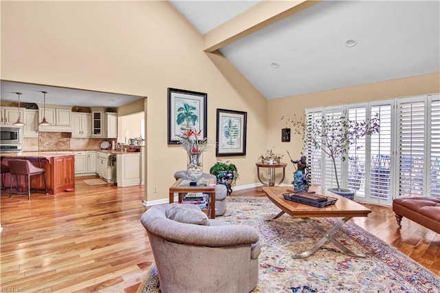 living room with beam ceiling, light hardwood / wood-style flooring, and high vaulted ceiling