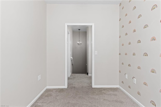 empty room with light carpet and a chandelier