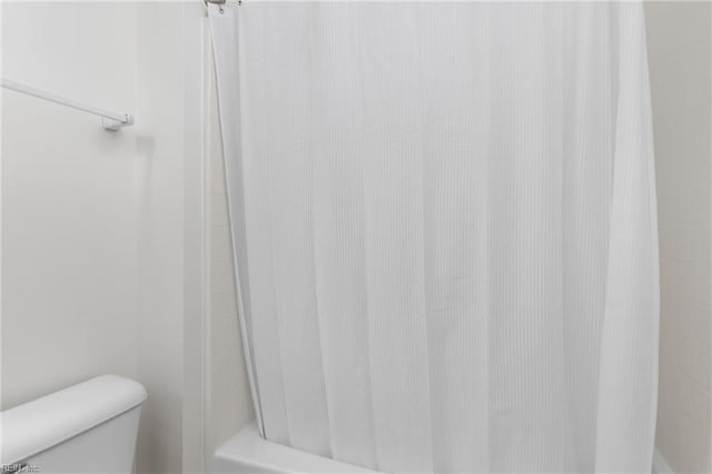 bathroom featuring a shower with shower curtain and toilet