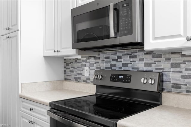 kitchen with backsplash, range with electric stovetop, and white cabinets