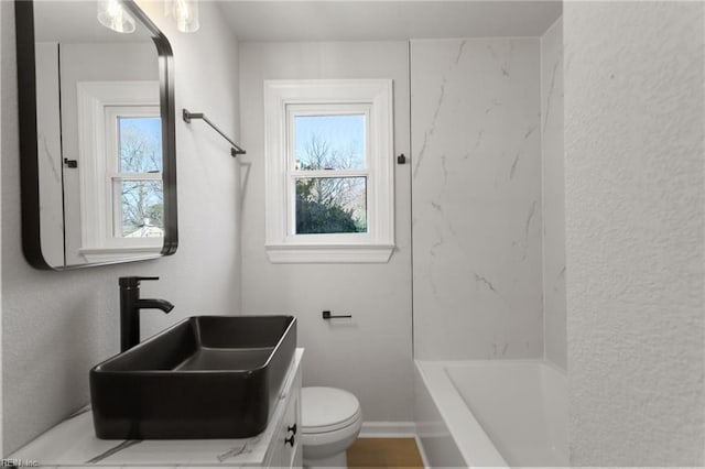 full bathroom featuring washtub / shower combination, vanity, and toilet