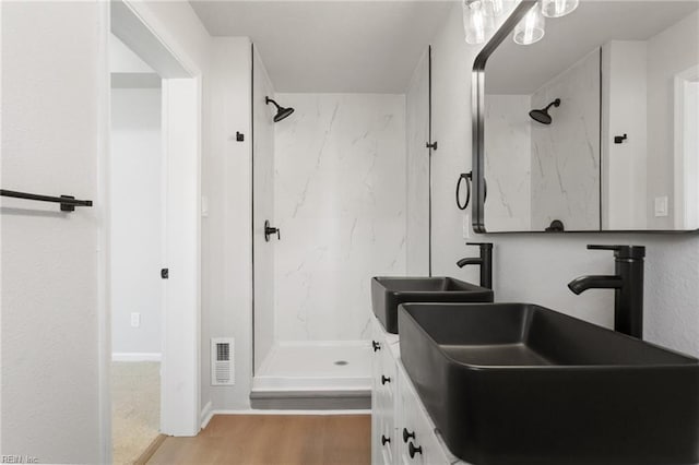 bathroom featuring tiled shower, vanity, and hardwood / wood-style floors