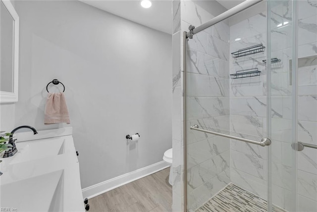 bathroom with hardwood / wood-style flooring, vanity, toilet, and a shower with door