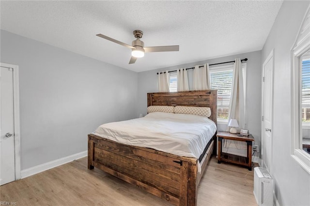 bedroom with a textured ceiling, light hardwood / wood-style floors, and ceiling fan