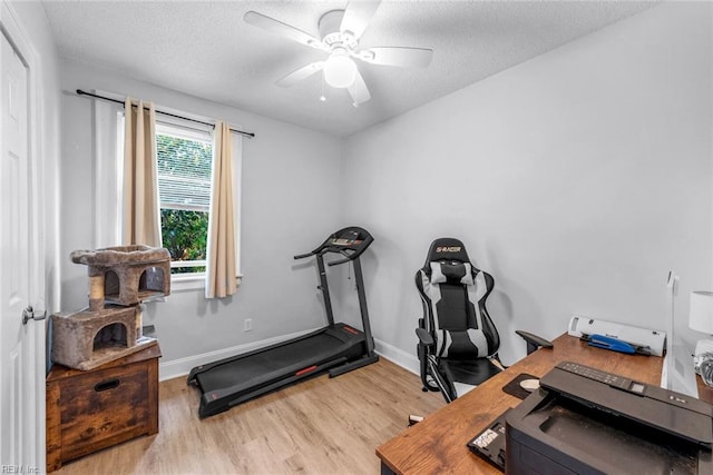 exercise room with a textured ceiling, light hardwood / wood-style flooring, and ceiling fan