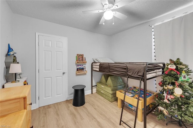 bedroom featuring ceiling fan, light hardwood / wood-style floors, and a textured ceiling