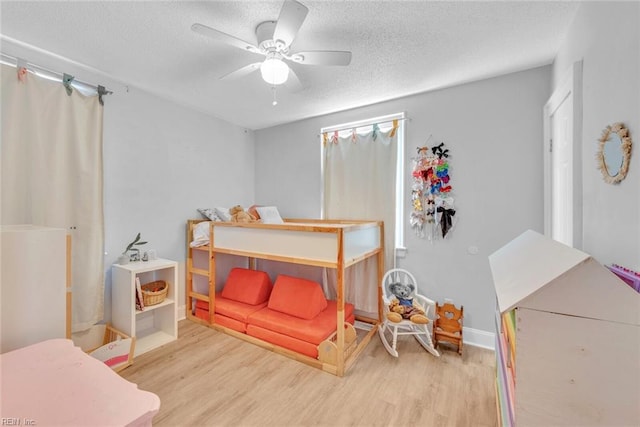 bedroom with ceiling fan, light hardwood / wood-style flooring, and a textured ceiling