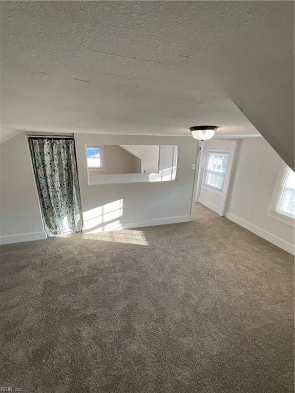 carpeted spare room with plenty of natural light and a textured ceiling